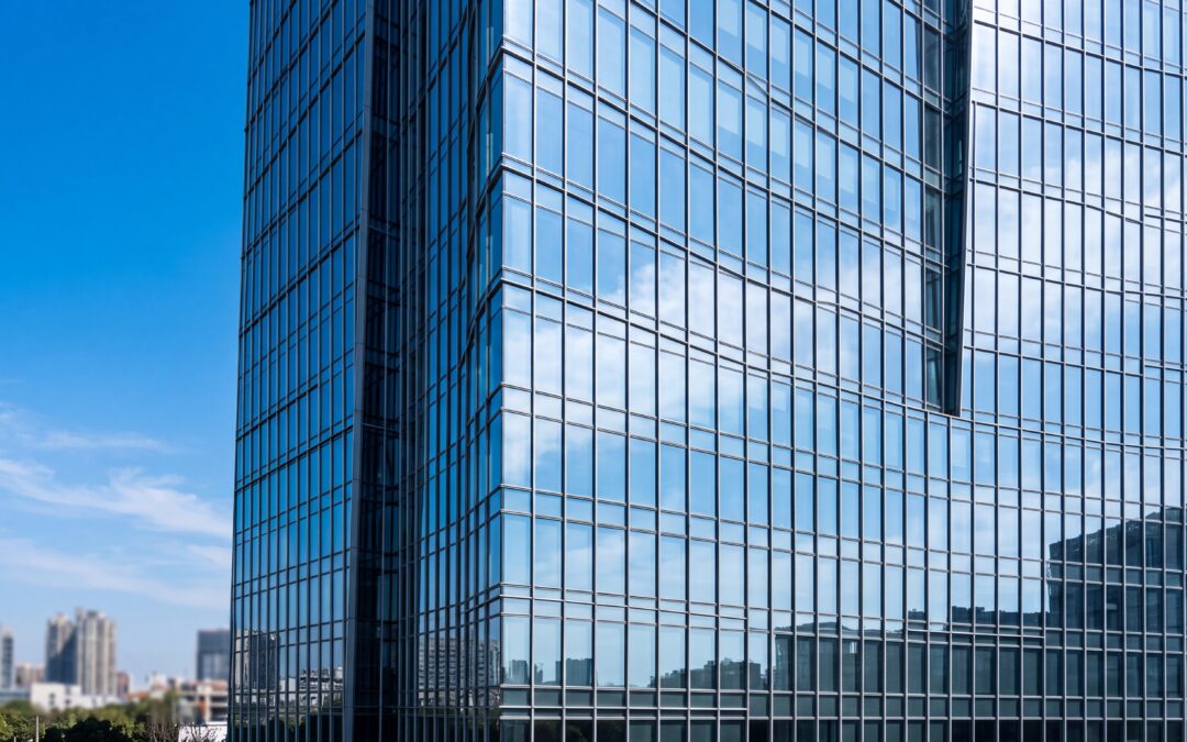 Clean exterior glass facade of a modern commercial office building reflecting a blue sky
